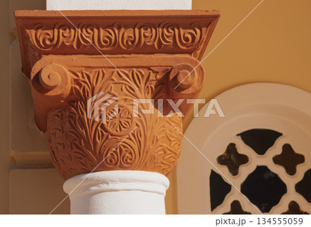 Detailed terracotta column capital with floral designs in a historical building during daylight Detailed terracotta column capital with floral designs in a historical building during daylight 134555059