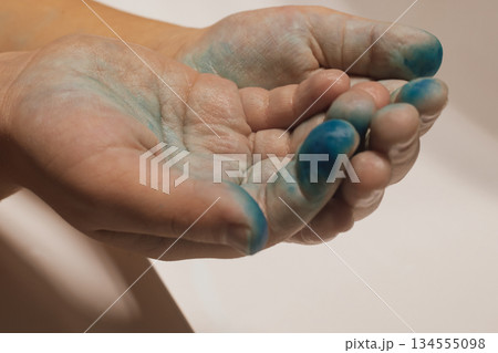 Messy hands: a child's hand covered in bright paint after a creative art session 134555098