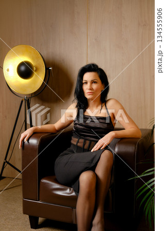 Woman sitting on brown chair with light in background during indoor session 134555906