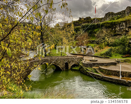 Ancient stone bridge overlooking verdant flowing river scene 134556578