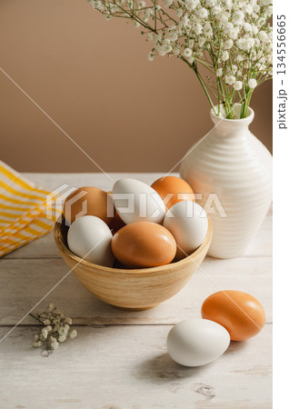Easter eggs background. White eggs in wooden bowl and gypsophila flowers in a vase. Spring holiday 134556665