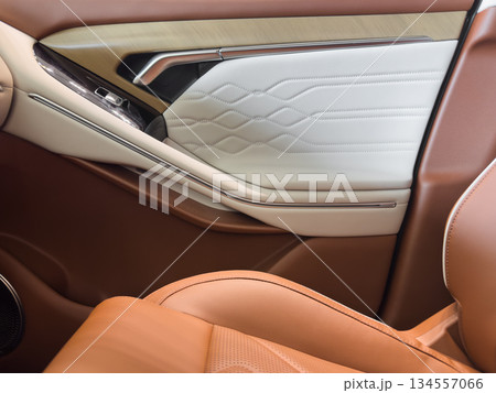 Modern luxury car brown leather interior. Part of orange leather car seat details with white stitching. Interior of prestige car. Comfortable perforated leather seats. Perforated leather. 134557066