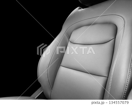 Modern luxury car black leather interior. Part of black leather car seat details with white stitching. Interior of prestige car. Perforated leather seats isolated on black. Perforated leather. Modern luxury car black leather interior. Part of black leather car seat details with white stitching. Interior of prestige car. Perforated leather seats isolated on black. Perforated leather. 134557079