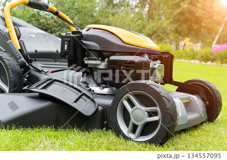 Mowing lawns. Lawn mower on green grass. Mower grass equipment. Mowing gardener care work tool close up view. Soft lighting Mowing lawns. Lawn mower on green grass. Mower grass equipment. Mowing gardener care work tool close up view. Soft lighting 134557095