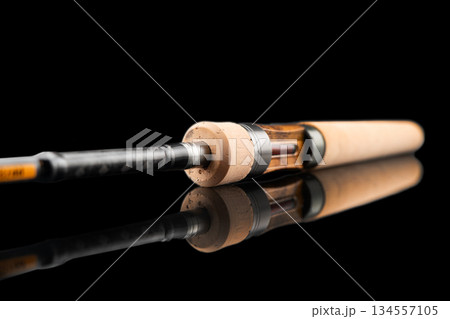 Fishing rod spinning with the line close-up. Fishing rod isolated on black background. Fishing rod rings. Tackle. Fishing spinning reel. 134557105