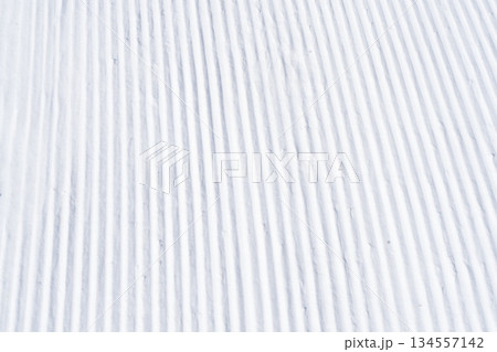 Close up of groomed tracks on a slope in a downhill ski resort. Close-up straight line rows of freshly prepared groomed ski slope Close up of groomed tracks on a slope in a downhill ski resort. Close-up straight line rows of freshly prepared groomed ski slope 134557142