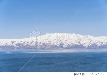 Aerial panorama view snow covered mountains. Snowy mountain ridge on winter sunrise. Stunning mountains range covered with snow over beautiful lake Aerial panorama view snow covered mountains. Snowy mountain ridge on winter sunrise. Stunning mountains range covered with snow over beautiful lake 134557152