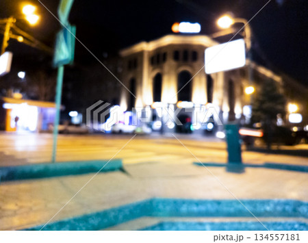 Blurred background. Night city. Blurred silhouette of buildings, bokeh spots of glowing lanterns. Blurred view of city street.Bokeh effect. Defocused night street with bokeh blur of street lights 134557181