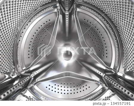 Washing machine drum close up. Washing machine background. Inside the washing machine. Metal washing machine drum. Perforated shiny metal 134557191