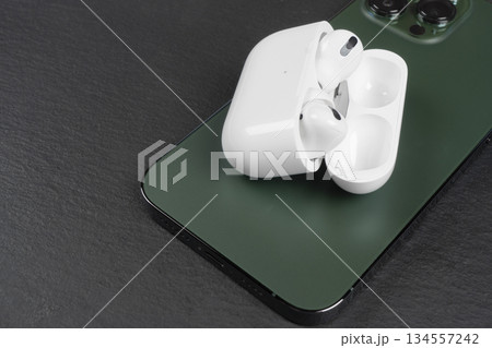 Modern wireless earbuds headphones with charging case iand smartphone on stone table background. Earphones for smartphone and tablet Modern wireless earbuds headphones with charging case iand smartphone on stone table background. Earphones for smartphone and tablet 134557242