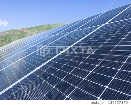 Blue Solar panel over blue sky, mountains, sun and clouds. Solar panels pattern for sustainable energy. Renewable solar energy. Alternative energy. 134557570