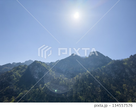 Scenic aerial mountain view to green forest valley in sunlight among mountain ranges and hills on horizon. Green landscape with sunlight mountains. Scenic aerial mountain view to green forest valley in sunlight among mountain ranges and hills on horizon. Green landscape with sunlight mountains. 134557576