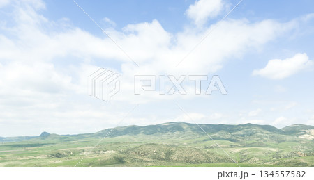 Scenic aerial mountain view to green forest valley in sunlight among mountain ranges and hills on horizon. Green landscape with sunlight mountains. Scenic aerial mountain view to green forest valley in sunlight among mountain ranges and hills on horizon. Green landscape with sunlight mountains. 134557582