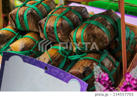 Close-up Macro View of Traditional Thai Dessert Khao Tom Mat Sticky Rice and Banana Wrapped in Steamed Banana Leaves with Vivid Green Rope Ties 134557703