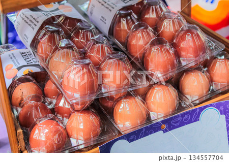 Multiple trays of raw brown chicken eggs displayed in transparent, protective plastic packaging at a grocery store or traditional market. Multiple trays of raw brown chicken eggs displayed in transparent, protective plastic packaging at a grocery store or traditional market. 134557704