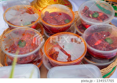 Close-up high angle shot of homemade spicy Sambal, a traditional Indonesian condiment, stored in multiple commercial transparent plastic jars. Close-up high angle shot of homemade spicy Sambal, a traditional Indonesian condiment, stored in multiple commercial transparent plastic jars. 134557705