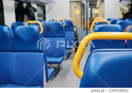 Empty blue passenger seats with yellow handles inside modern train carriage, showing travel Empty blue passenger seats with yellow handles inside modern train carriage, showing travel 134558052