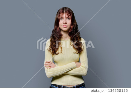 Portrait of serious confident teenage girl with crossed arms on gray background Portrait of serious confident teenage girl with crossed arms on gray background 134558136