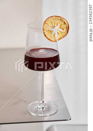 Elegant Drink Presentation, Sophisticated Scene Showcasing Red Wine And Citrus Touch In Minimal Setting 134562397