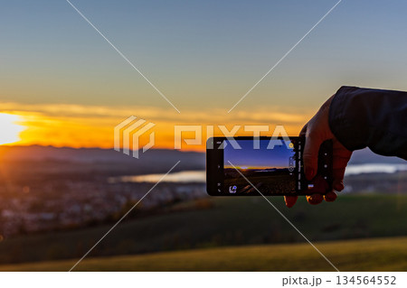 Taking a photo of a golden sunset over the lake with a smartphone 134564552