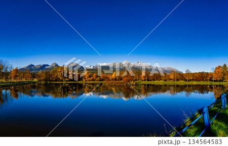 Snowy High Tatras peaks reflected in calm lake water during autumn morning 134564583