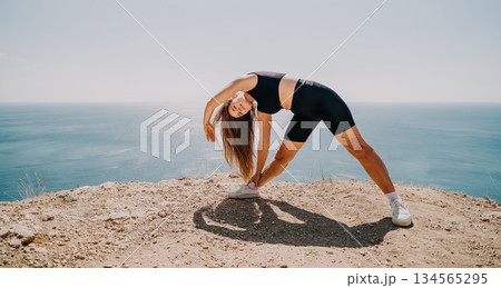 Woman Stretching on Cliffside with Ocean View Woman Stretching on Cliffside with Ocean View 134565295