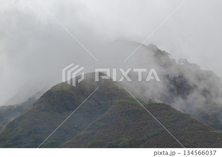 Mountain peaks covered by dense fog and low-lying mist in a cloudy atmospheric natural landscape 134566037