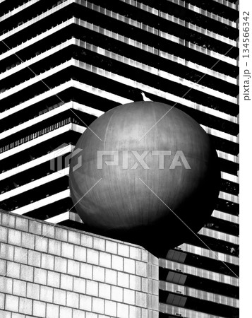Sphere on pedestal before striped modern building in a bold black and white city scene 134566342