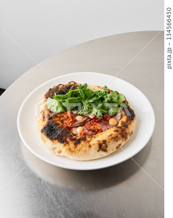 Charred Neapolitan pizza garnished with fresh greens and melted cheese Charred Neapolitan pizza garnished with fresh greens and melted cheese 134566450