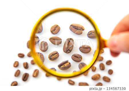 Magnifying glass and coffee beans arranged on a plain white background 134567330