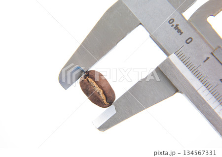 striking close-up of a coffee bean under a caliper grip, captured against a white background 134567331