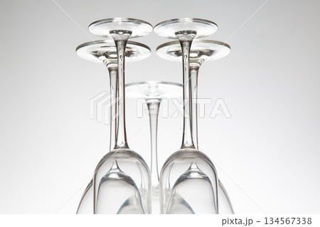 Five wine glasses with slender stems line up, their reflections visible on a reflective surface Five wine glasses with slender stems line up, their reflections visible on a reflective surface 134567338