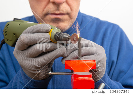 Male locksmith worker processes metal with engraving drill cutting. Male locksmith worker processes metal with engraving drill cutting. 134567343