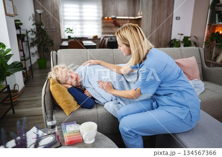Caregiver offers comfort to elderly patient in cozy living room setting Caregiver offers comfort to elderly patient in cozy living room setting 134567366