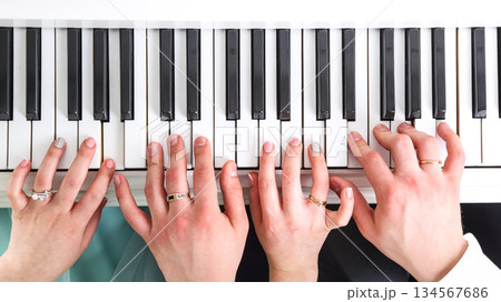 Multiple hands playing piano keys in a collaborative musical session Multiple hands playing piano keys in a collaborative musical session 134567686