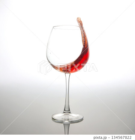 A dramatic splash of red wine captured mid-air, swirling inside a clear wine glass A dramatic splash of red wine captured mid-air, swirling inside a clear wine glass 134567822