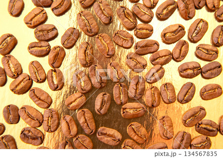 Roasted coffee beans in an oval formation on a reflective golden surface Roasted coffee beans in an oval formation on a reflective golden surface 134567835