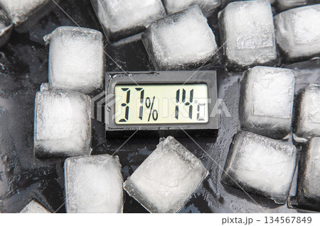 digital thermometer for measuring air temperature and humidity against the background of frozen ice 134567849