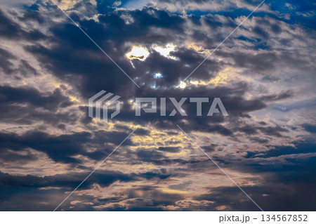 Sunset sky with layered clouds in various shades of blue, gray, and gold. Sunset sky with layered clouds in various shades of blue, gray, and gold. 134567852