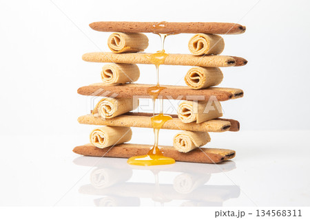 Fresh flower honey flows and drips onto herdry crispy cookie sticks. Dessert snack food. 134568311