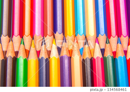 Brightly colored pencils in a layered grid arrangement against a white surface 134568461