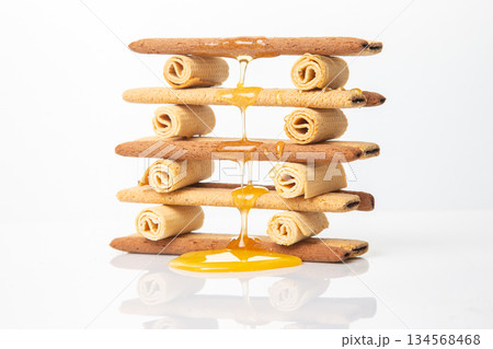 Fresh flower honey flows and drips onto herdry crispy cookie sticks. Dessert snack food. 134568468