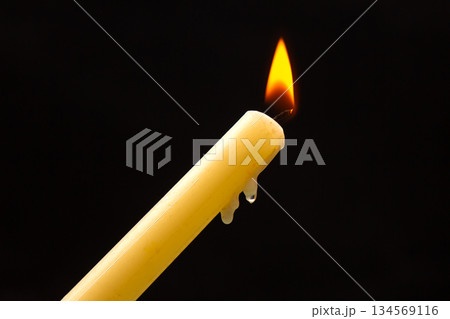 Lighting a candle with a wooden match on a dark background. Burning candle fire Lighting a candle with a wooden match on a dark background. Burning candle fire 134569116