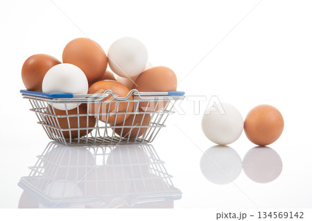 A small metal shopping basket filled with white and brown eggs 134569142