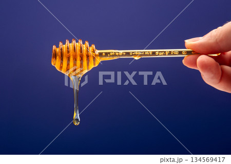 fresh fragrant honey drips from a spoon into a plate on a colored background fresh fragrant honey drips from a spoon into a plate on a colored background 134569417