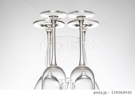 A row of five empty wine glasses with elegant stems, reflecting perfectly on a glossy table A row of five empty wine glasses with elegant stems, reflecting perfectly on a glossy table 134569430