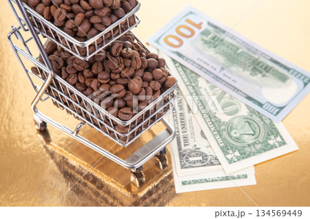 A tiny cart filled with coffee beans sits next to 100 bills A tiny cart filled with coffee beans sits next to 100 bills 134569449