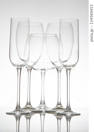 A row of five empty wine glasses with elegant stems, reflecting perfectly on a glossy table A row of five empty wine glasses with elegant stems, reflecting perfectly on a glossy table 134569453