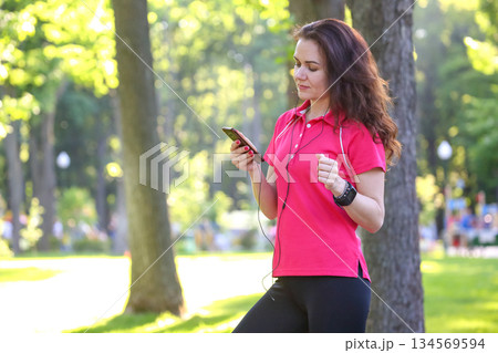 Woman listens to music while enjoying a sunny day in the park 134569594