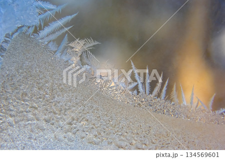 Frost patterns forming intricate designs on a window in winter 134569601